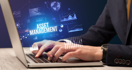 Businessman working on laptop with ASSET MANAGEMENT inscription, new business concept