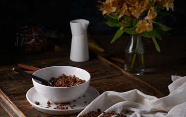 Chocolate granola in white bowl. Dark key photo style. cozy home, homemade breakfast
