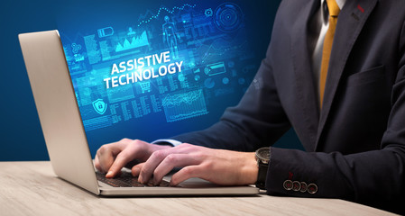 Businessman working on laptop with ASSISTIVE TECHNOLOGY inscription, cyber technology concept