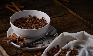 Chocolate granola in white bowl. Dark key photo style. cozy home, homemade breakfast