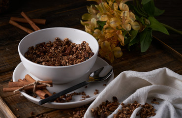 Chocolate granola in white bowl. Dark key photo style. cozy home, homemade breakfast