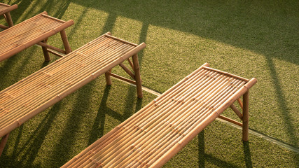 High angle view of bamboo benches on green turf with sunlight and shadow on surface