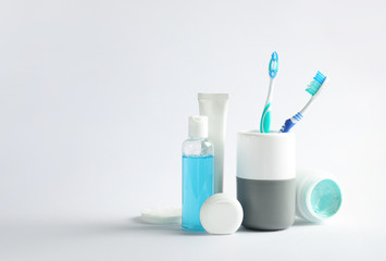 Plastic toothbrushes in cup and other dental products on white background