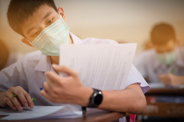 The Asian high school students in a white school uniform wearing the masks to do final exams in the midst of Coronavirus disease 2019 (COVID-19) epidemic and PM 2.5.