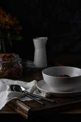 Chocolate granola in white bowl. Dark key photo style. cozy home, homemade breakfast