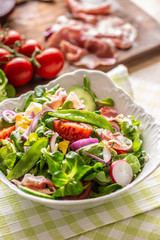 Fresh spring salad with green leaves tomatoes egg radish red onion young peas prosciutto feta cheese and olive oil