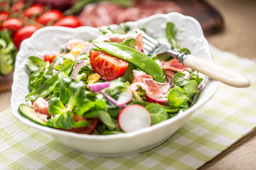Fresh spring salad with green leaves tomatoes egg radish red onion young peas prosciutto feta cheese and olive oil