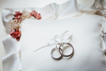 Two white gold wedding rings tied with a bow