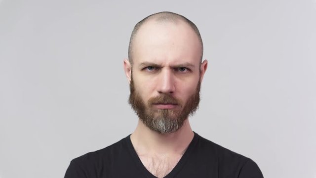 Strict man raising finger in warning gesture over white background. Serious dissatisfied man making admonishing gesture, disapproval sign, saying no.