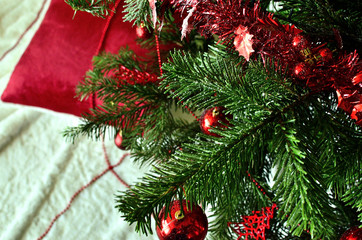Decorated Christmas Tree with Red Ornaments and a Red Fluffy Pillow near the Tree