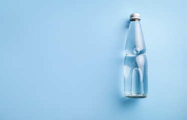 Glass water bottle on blue background