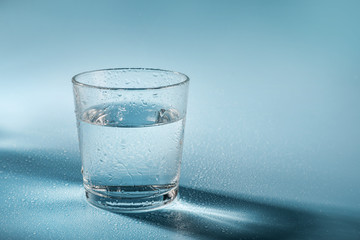 Glass of water on blue background