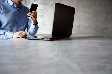Postura mężczyzny pracującego przy komputerze trzymający w dłoni telefon komórkowy - obrazy, fototapety, plakaty