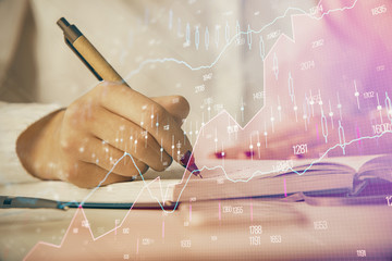 Multi exposure of woman's hands making notes with forex graph hologram. Concept stock market analysis.