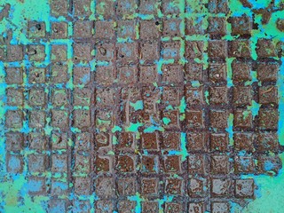 texture of a metal manhole from a well with peeling turquoise paint after rain