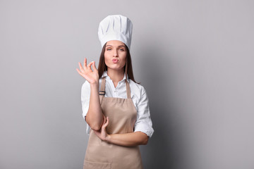 .Young woman in an apron with fresh bread on a gray background. Cook concept