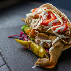 Massive kebab with vegetables and sauce over a rustic background