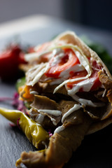 Massive kebab with vegetables and sauce over a rustic background