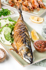 Grilled fish served with sauce, lemon, and fresh vegetables