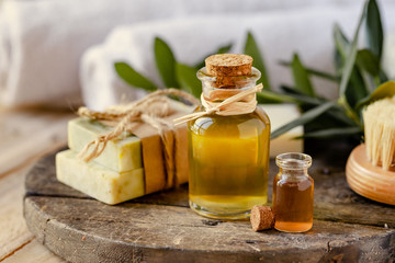 Obraz na płótnie Canvas Concept of natural ingredients in cosmetology for gentle skin care. Organic olive oil in glass bottle, handmade soap bars. Atmosphere of serenity and relax. Rustic wooden background, close up.