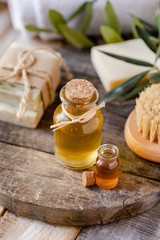 Concept of natural ingredients in cosmetology for gentle skin care. Organic olive oil in glass bottle, handmade soap bars. Atmosphere of serenity and relax. Rustic wooden background, close up.