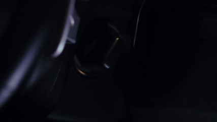 Female hand starting a car engine with ignition key at night time