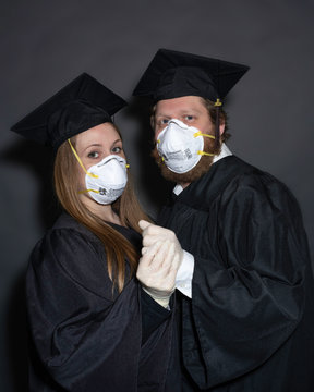 2 Quarantined Coronavirus COVID-19 Graduate Students With Masks In Graduation Cap And Gown For Cancelled Commencement Ceremony