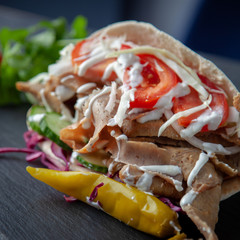 Massive kebab with vegetables and sauce over a rustic background