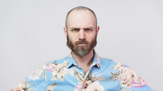 Slow motion strict man wearing hawaiian shirt raising finger in warning gesture over white background. Serious dissatisfied man making admonishing gesture.