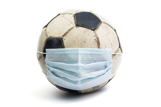 old battered shabby soccer ball with medical mask coronavirus covid 2019 euro 2020 on a white background isolate