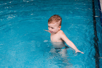 Fototapeta na wymiar wet and cute toddler child in swimming pool