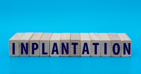 concept word INPLANTATION on cubes on a blue background