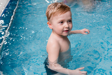 Fototapeta na wymiar wet and adorable toddler boy in swimming pool