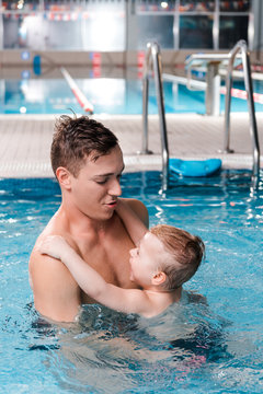 swim coach teaching cute toddler boy in swimming pool