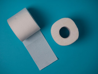 Two rolls of white toilet paper on a blue background top view.