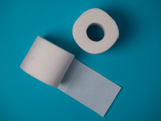 Two rolls of white toilet paper on a blue background top view.