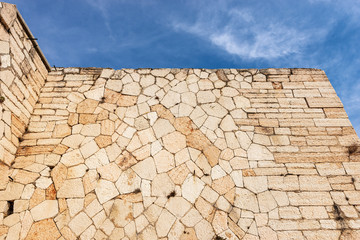 Closeup of an Austrian fortified wall made of irregular stone blocks on a blue sky with clouds