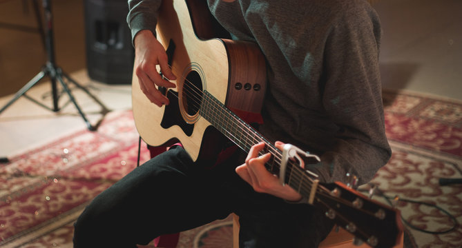 Young man playing on acoustic guitar