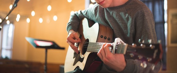Young man playing on acoustic guitar - obrazy, fototapety, plakaty