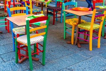 Outdoor furniture Set of coloured wooden chairs arranged in the street
