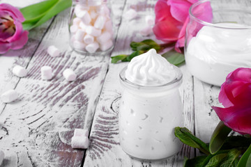 Marshmallow creme in glass jars on the white wooden table