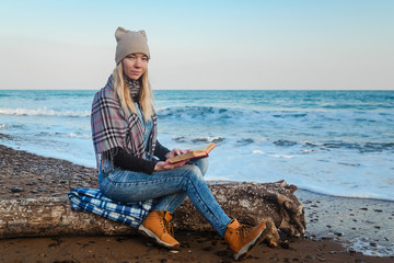Girl reads a book by the sea