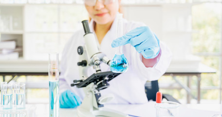 Asian woman scientist, researcher, technician, or student conducted research or experiment by using microscope which is scientific equipment in medical, chemistry or biology laboratory