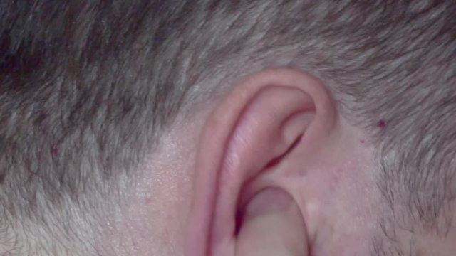 A man scratches his ear with finger