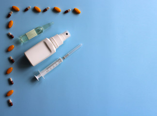 Antiseptic, ampoule, syringe, medicines and vitamins on a blue background. Covid19, coronavirus and epidemic content. Virus prevention and creating a vaccine against coronavirus. Copy space.
