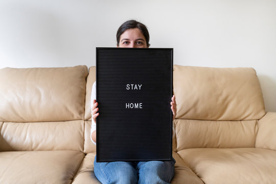 Healthy Woman Holding An Empty Blackboard With Message To Stay Home During Pandemic Development Of Covid 19 Viral Disease. Precautions List To Avoid Infection. Coronavirus Concept.