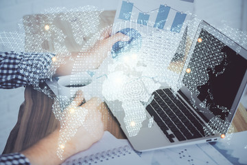 Double exposure of businessman working on laptop on background. International business hologram in...