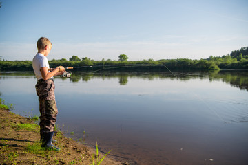 Photo of a young boy fishing outdoors on a summer day.