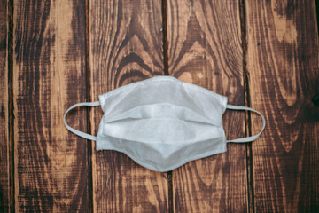 White medical mask lies on a wooden surface