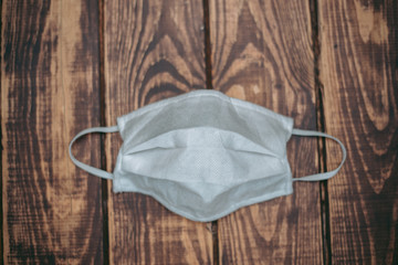 White medical mask lies on a wooden surface